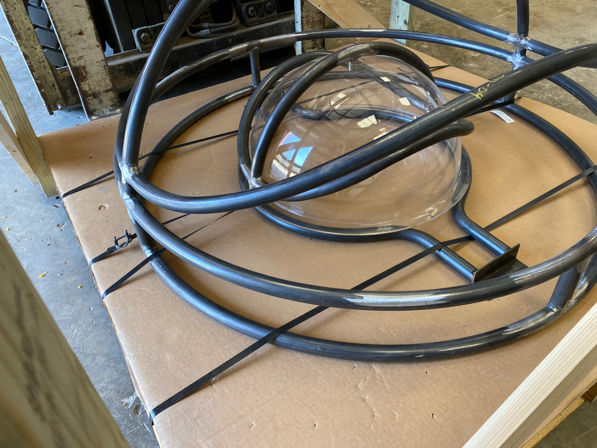 Detail of the acrylic dome strapped within the bent tube cage for shipping