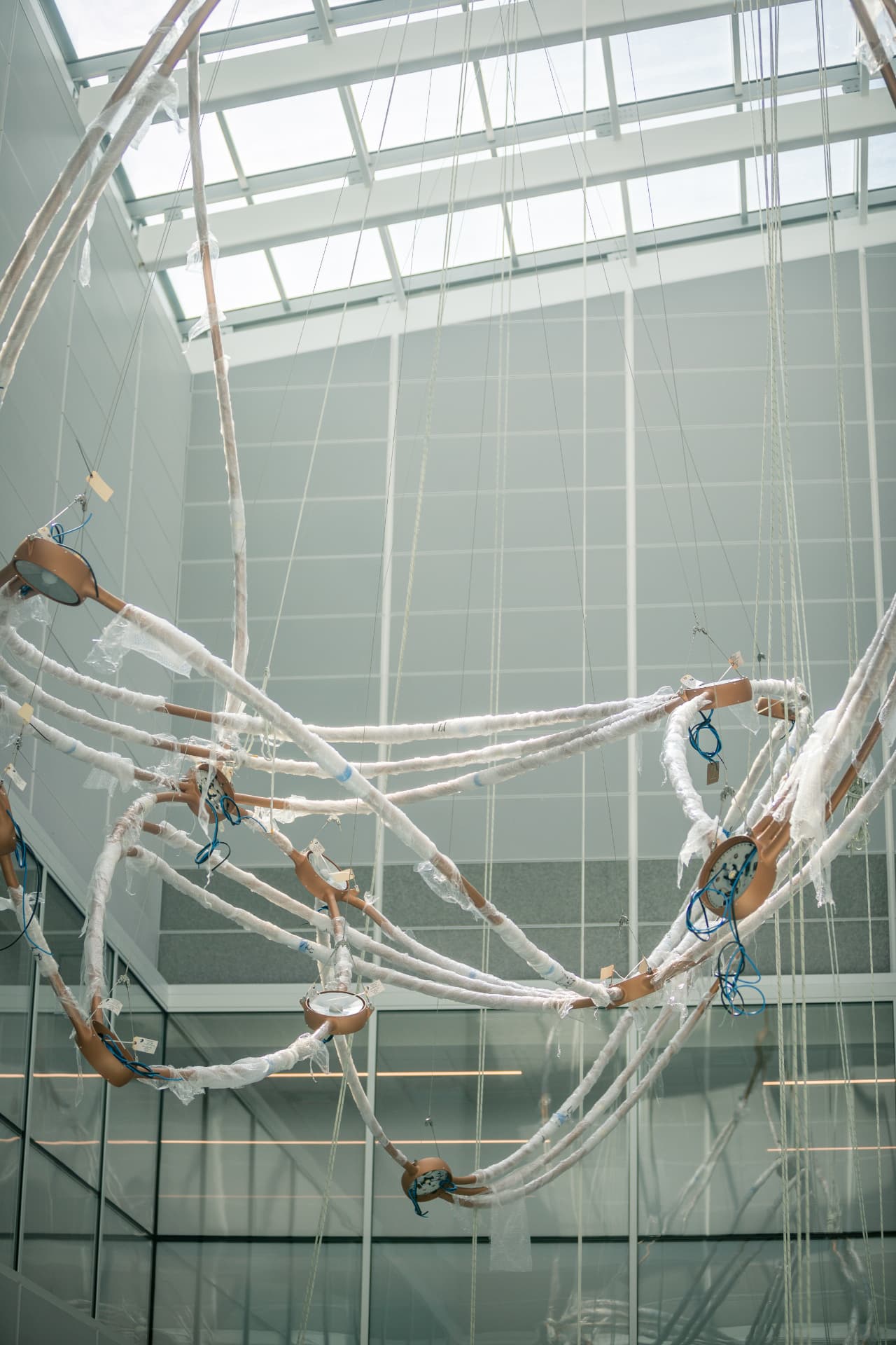 Large wrapped sculpture assembly suspended on rigging lines before final placement