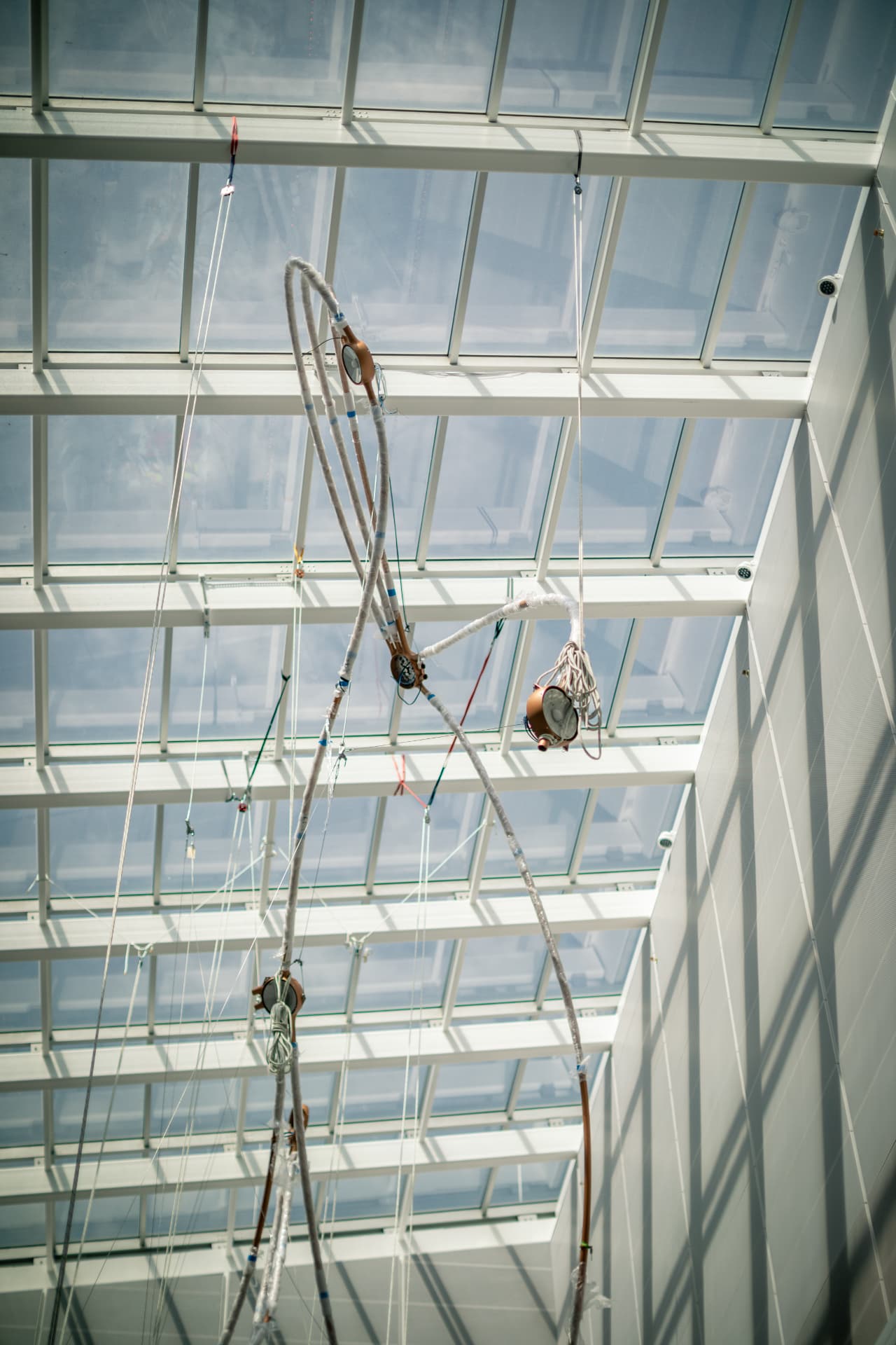 Wrapped copper arcs and star nodes hanging beneath the atrium skylight during install