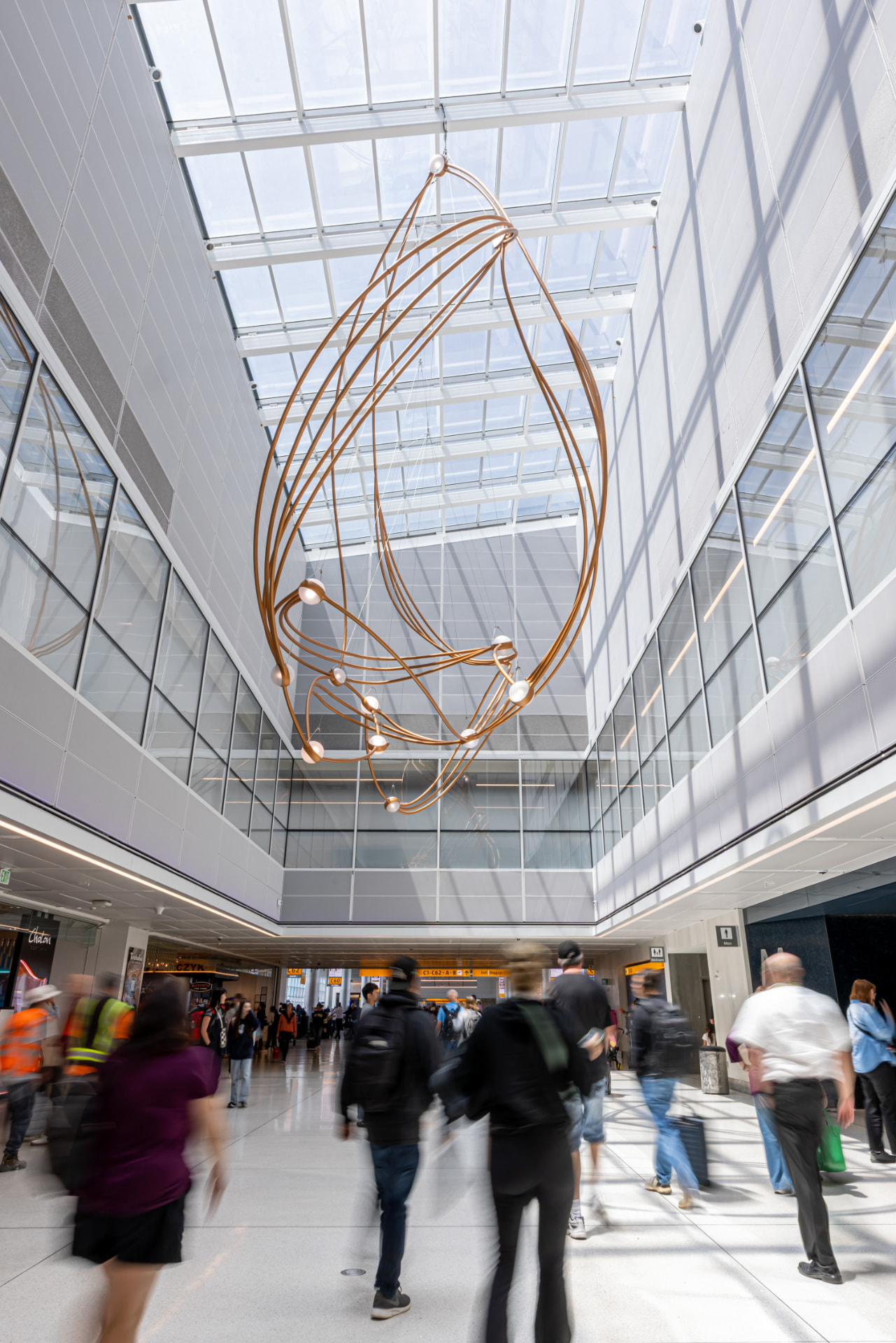 Vertical view of the sculpture's looping copper tubes beneath the skylight