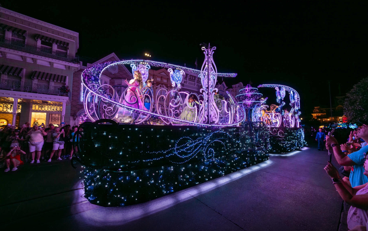 The Royal float in magenta and violet light passing crowds along Main Street