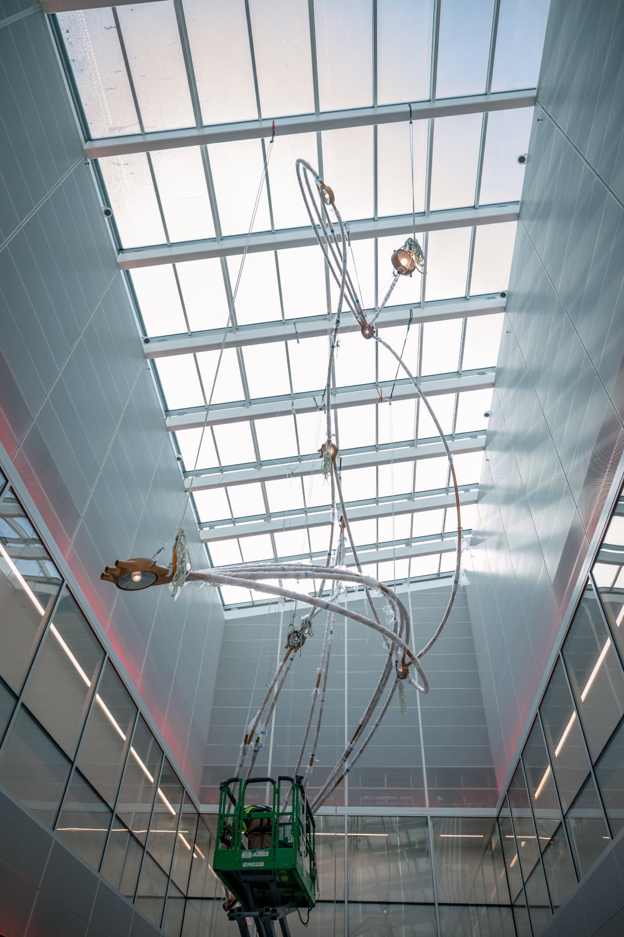 Sculpture geometry suspended in the atrium with an installer on a lift below