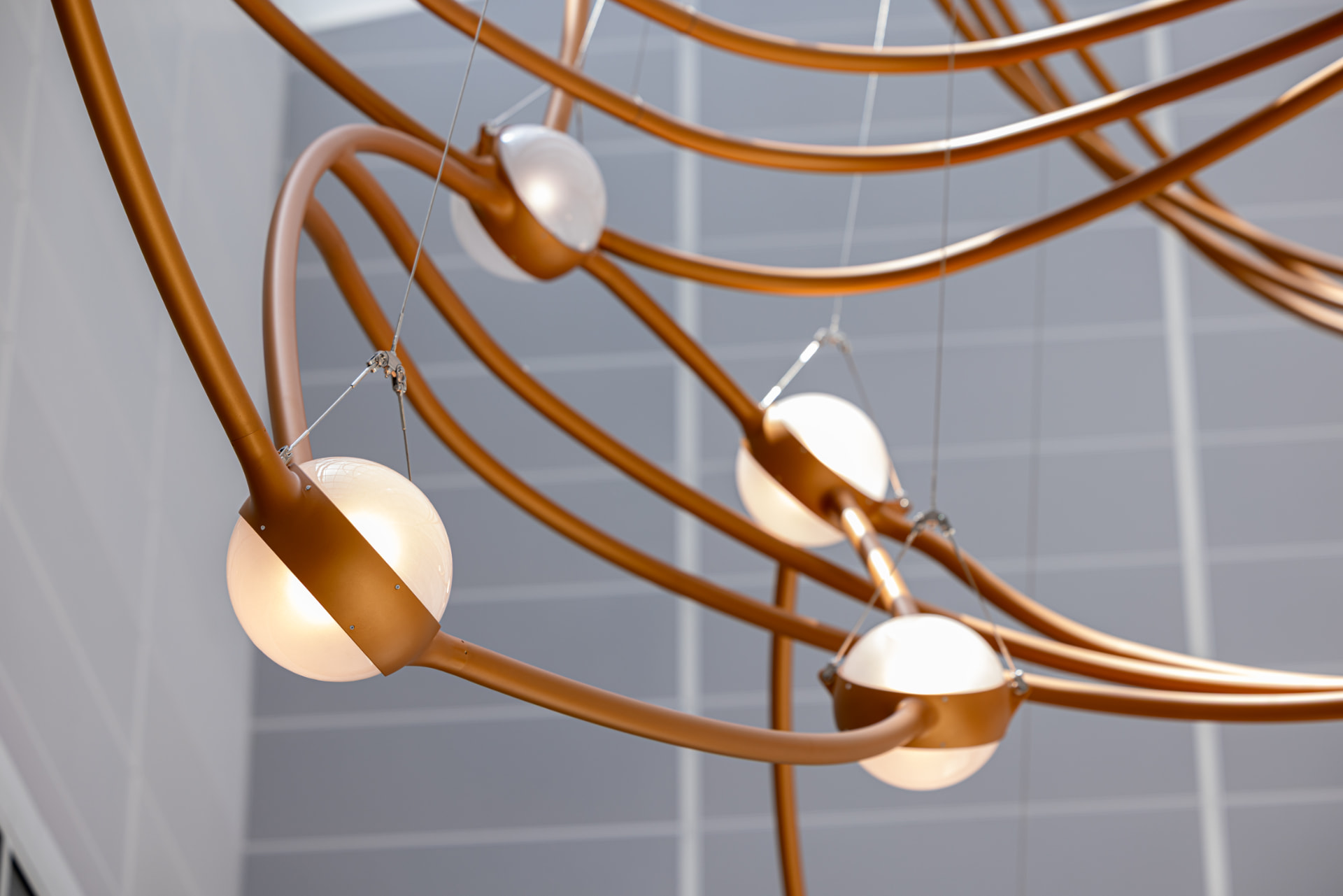 Row of glowing glass stars suspended along sweeping copper arcs