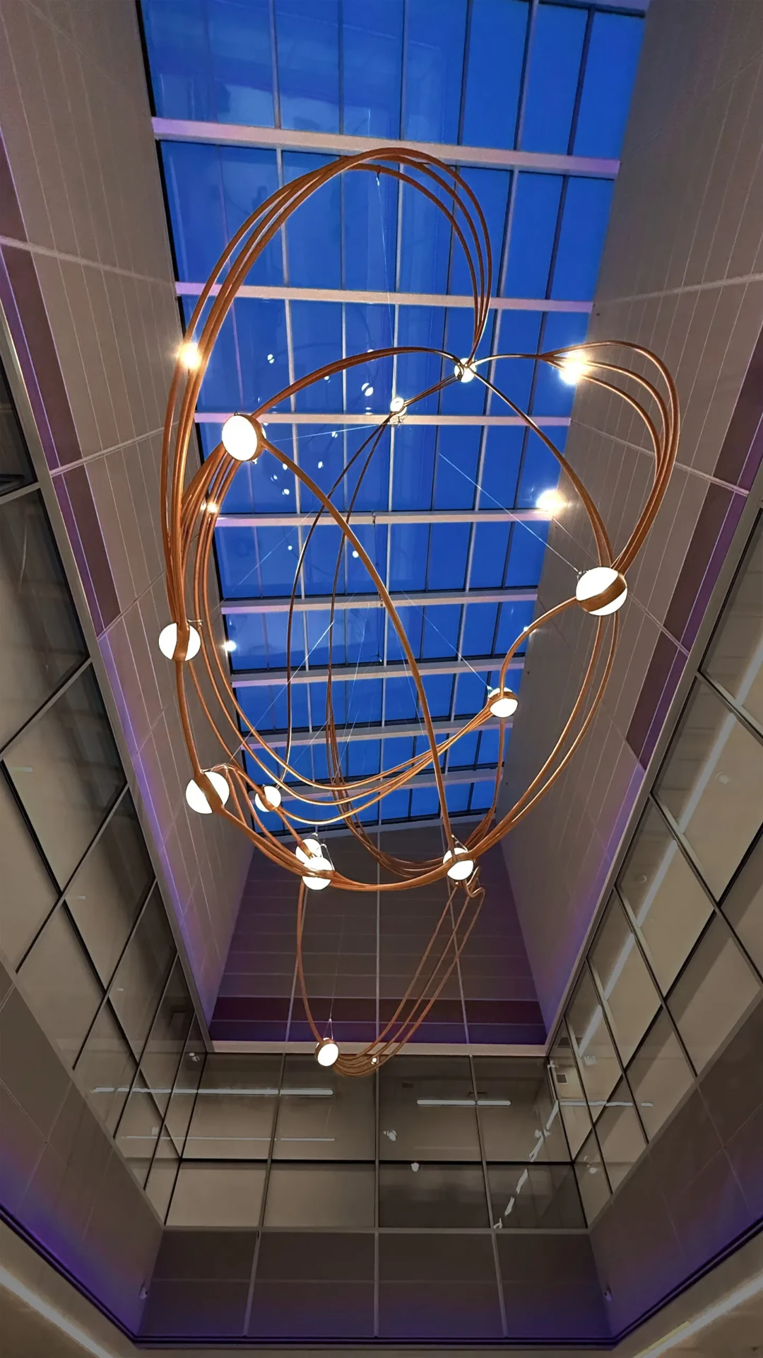 Constellations sculpture silhouetted against a blue backlit skylight