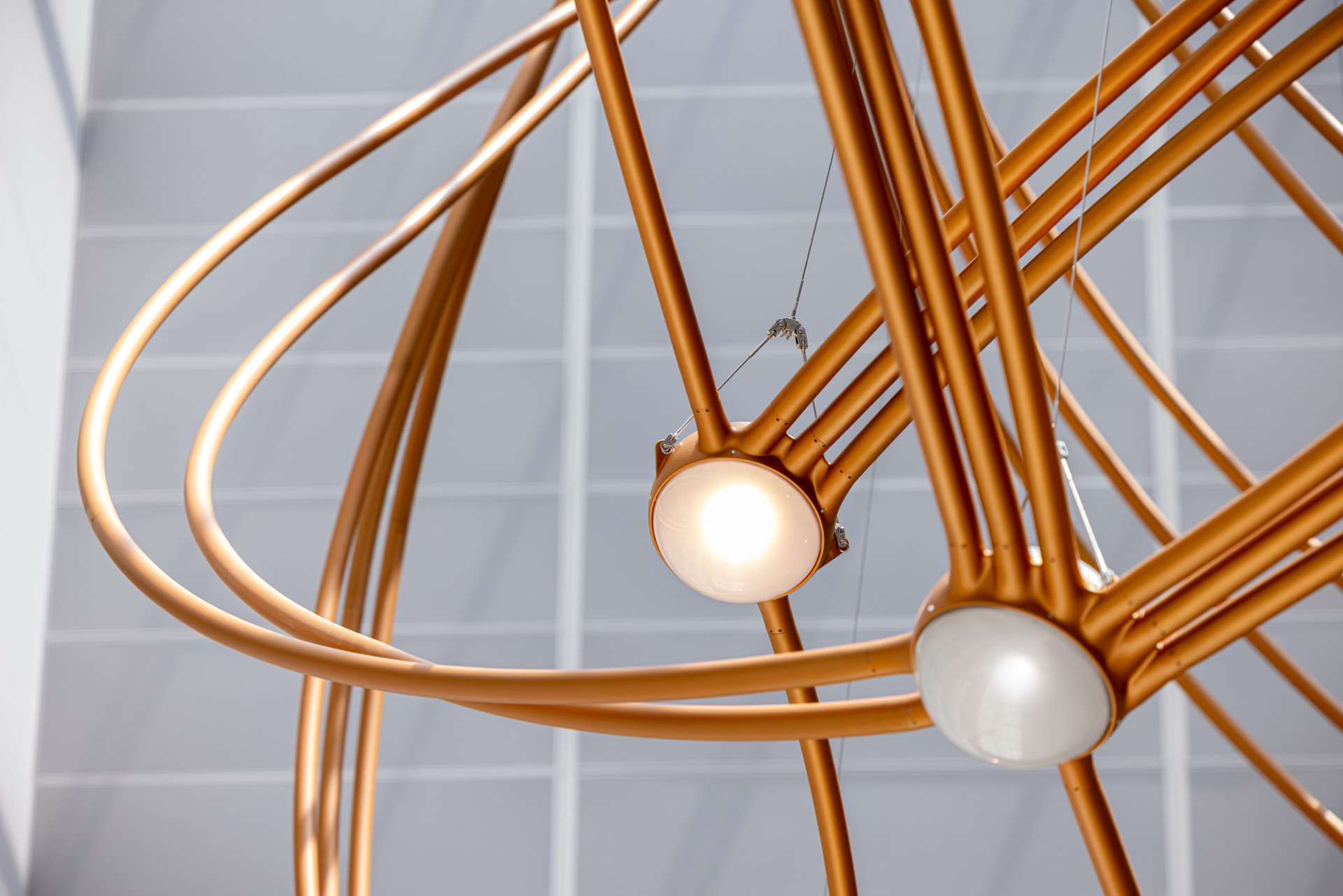 Illuminated globe nested within crossing copper tubes of the Constellations sculpture