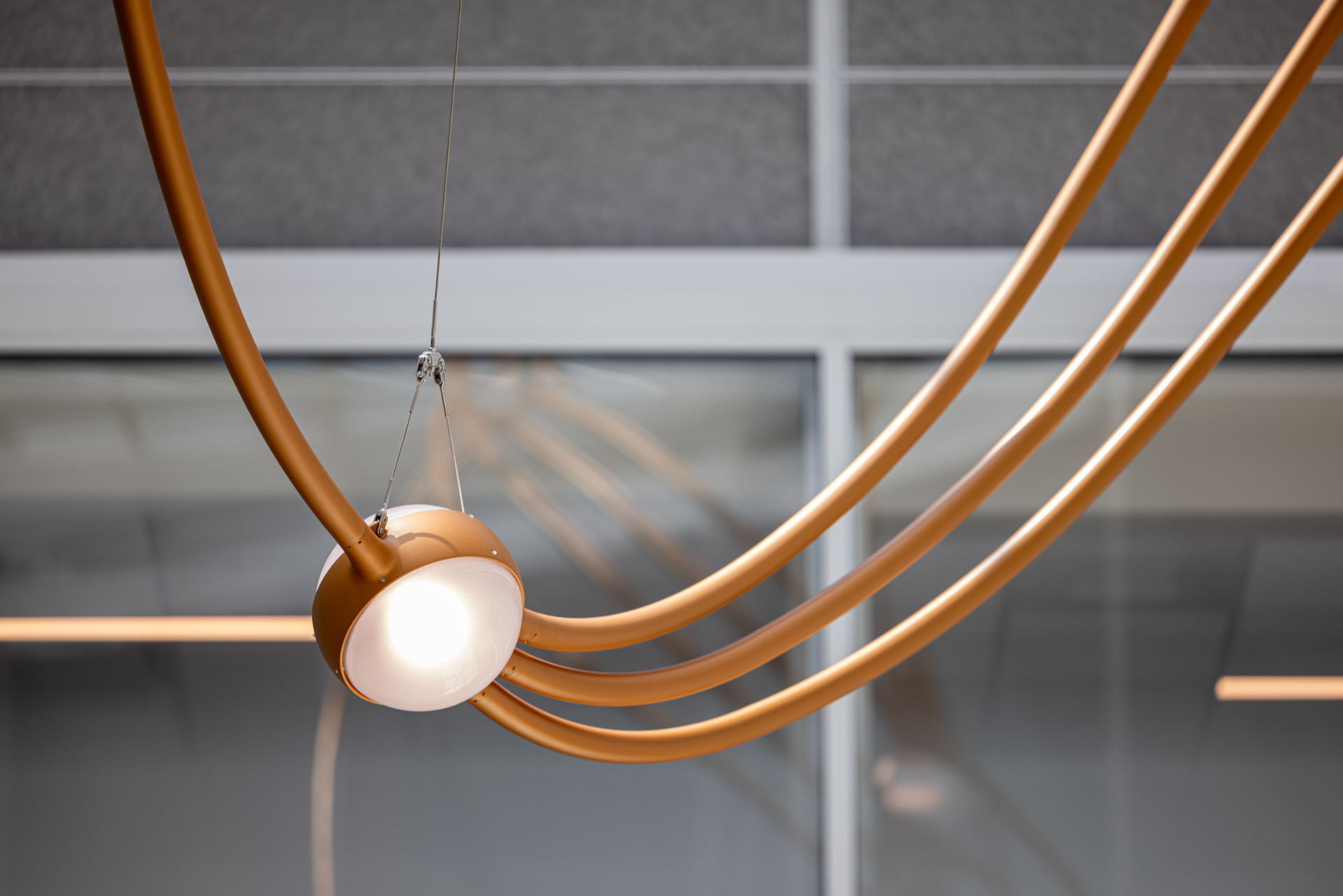 Single illuminated star node on a copper arc above an airport concourse