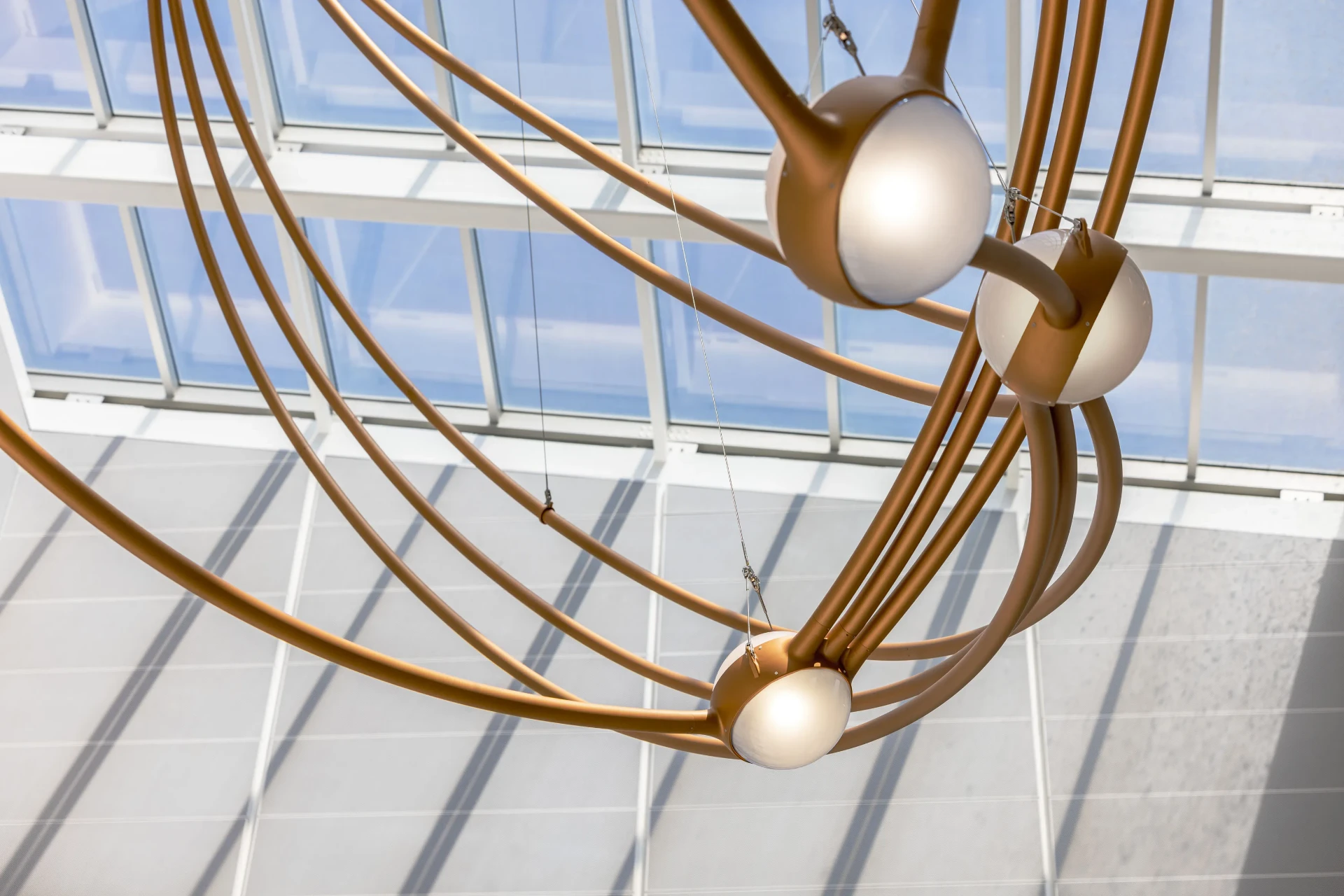 Copper arcs and frosted glass star nodes lit against the atrium skylight