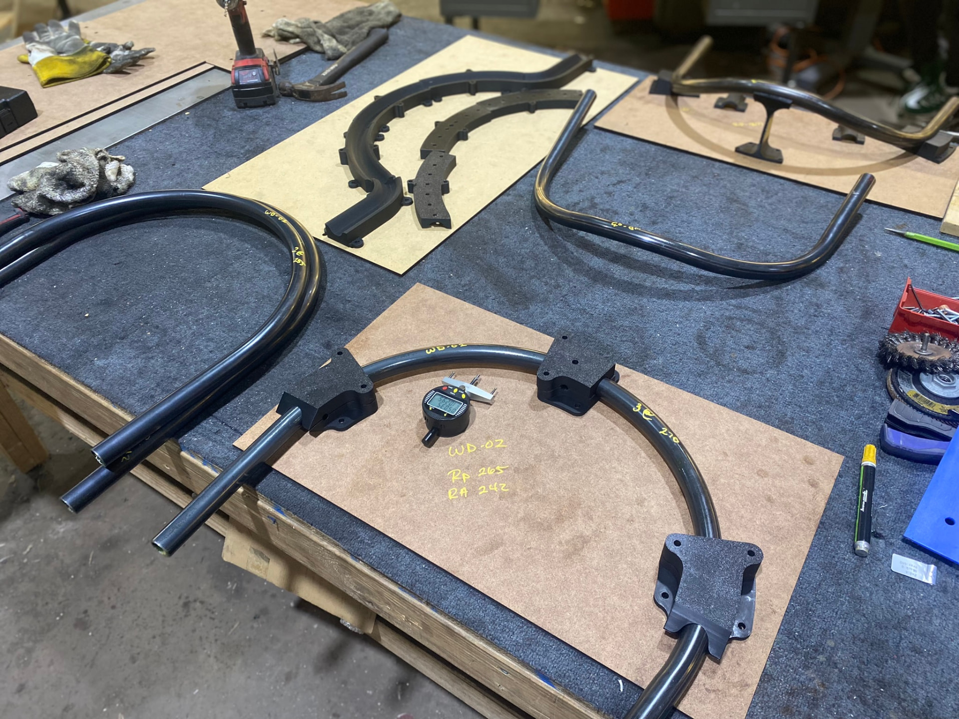 WD-02 arc fixtured on a layout board with bend radius notes and weld blocks