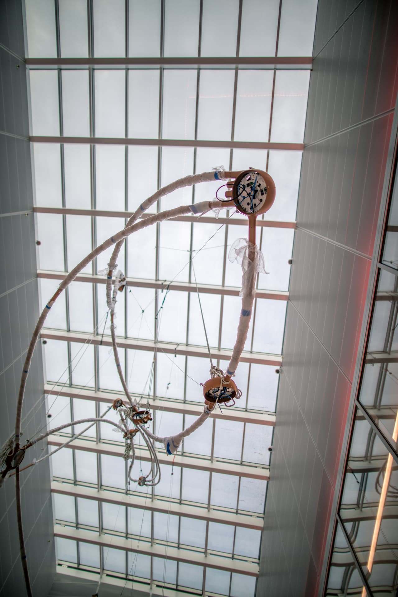 Wrapped sculpture arcs and star nodes hanging mid-installation against the skylight grid