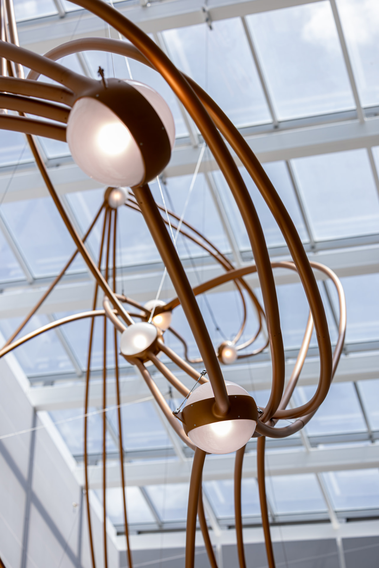 Copper arcs and lit star globes framed by the skylight grid