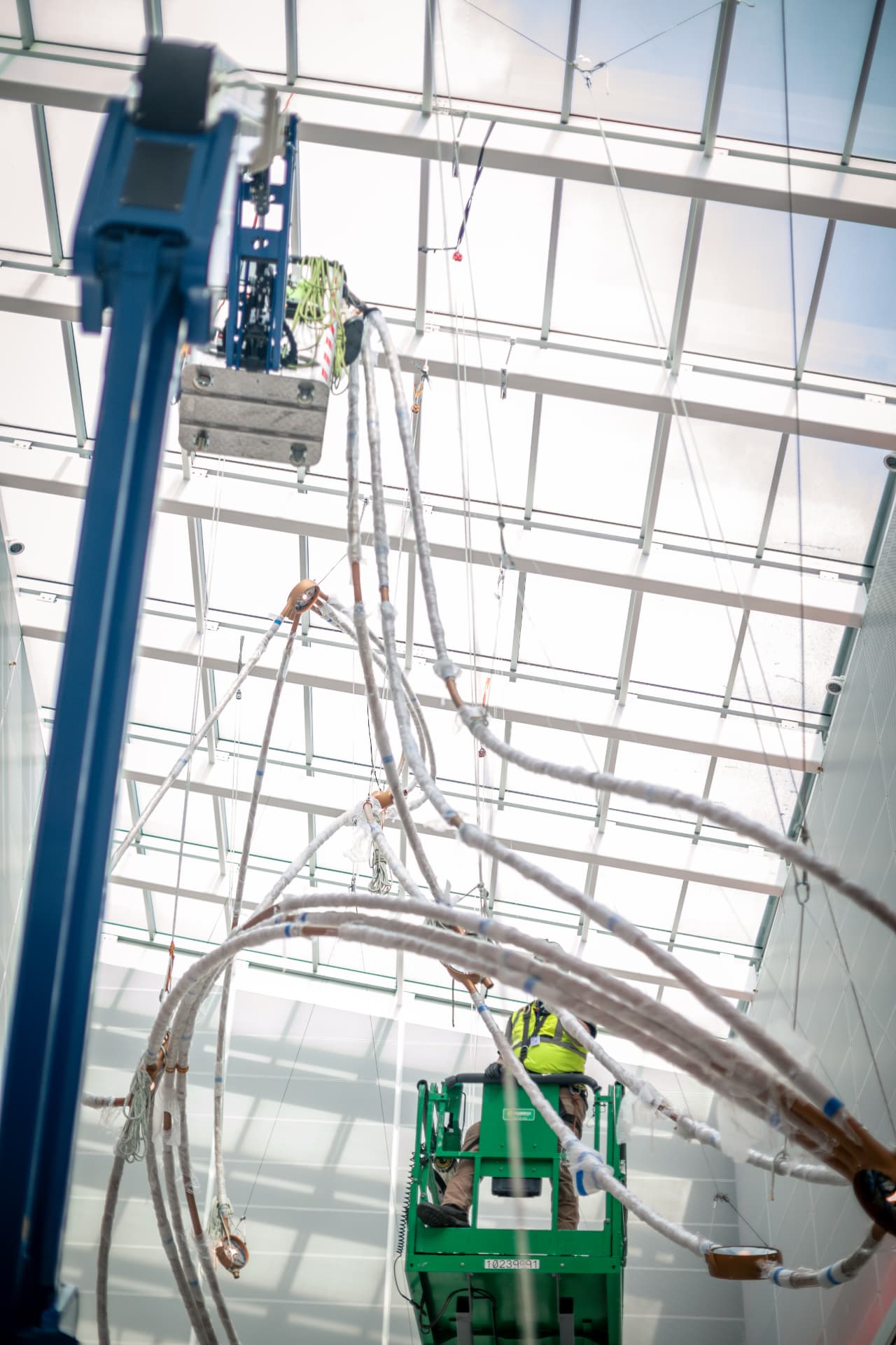 Installer on a lift guiding wrapped copper arcs into place