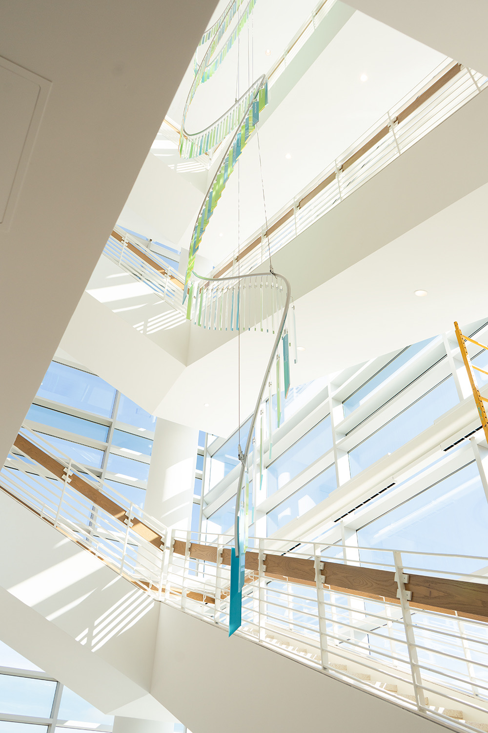 Upward view of the suspended curved tube spine and hanging glass blades in the atrium