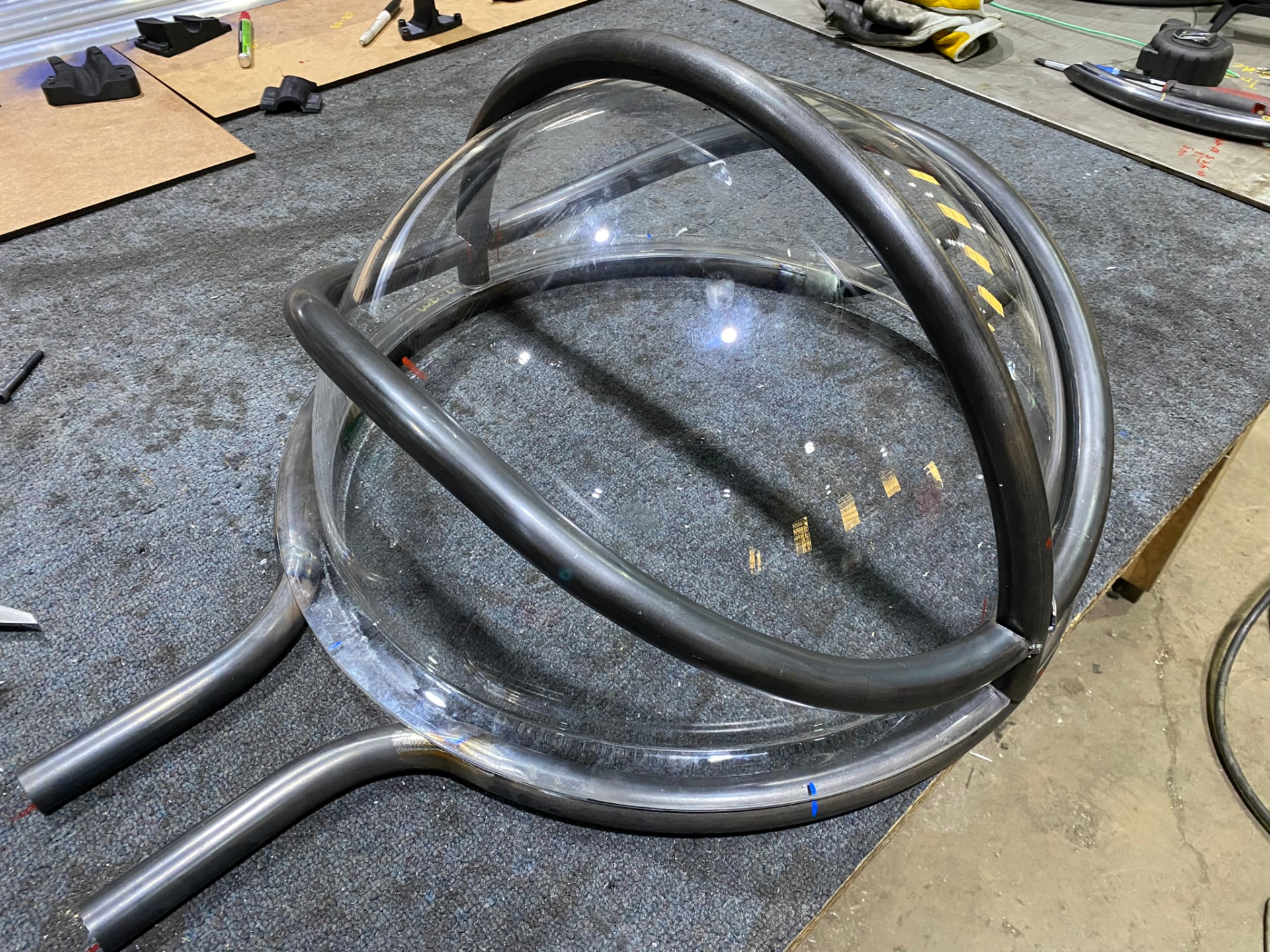 Bent tube arcs nested over the clear acrylic dome during trial assembly