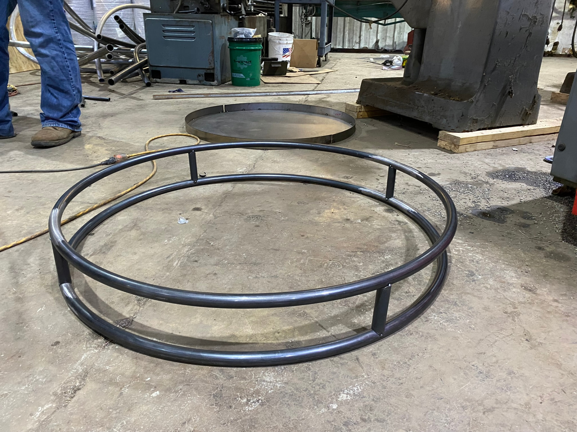 Welded double-ring pedestal base frame beside its deck plate on the shop floor